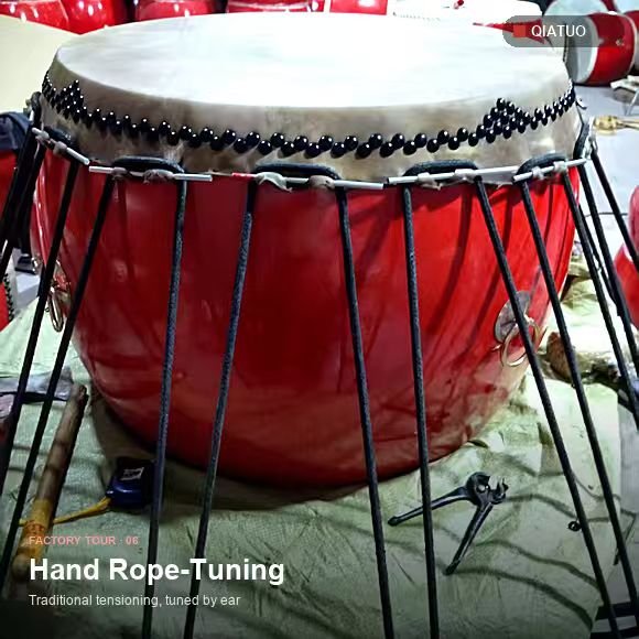 Large red drum hand rope-tuned on a black steel stand at the QiaTuo workshop
